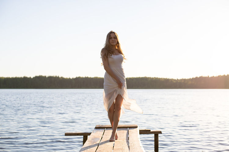 Side view of young woman standing by lake