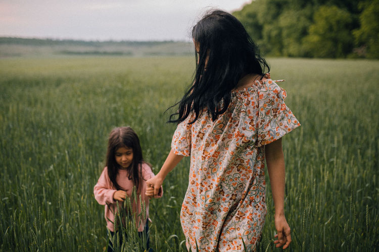 Happy mother walking with child in field at dusk