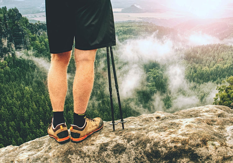 Hiker legs in fall nature. guy just relax. feets in trekking shoes and legs short running trousers