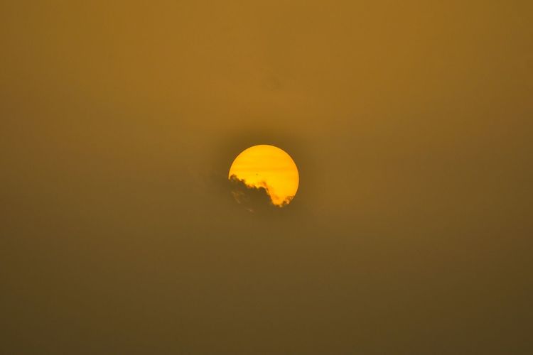 Low angle view of yellow moon against sky at sunset