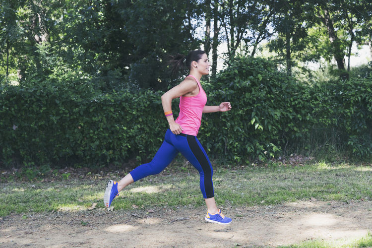 Side view of young woman running at park