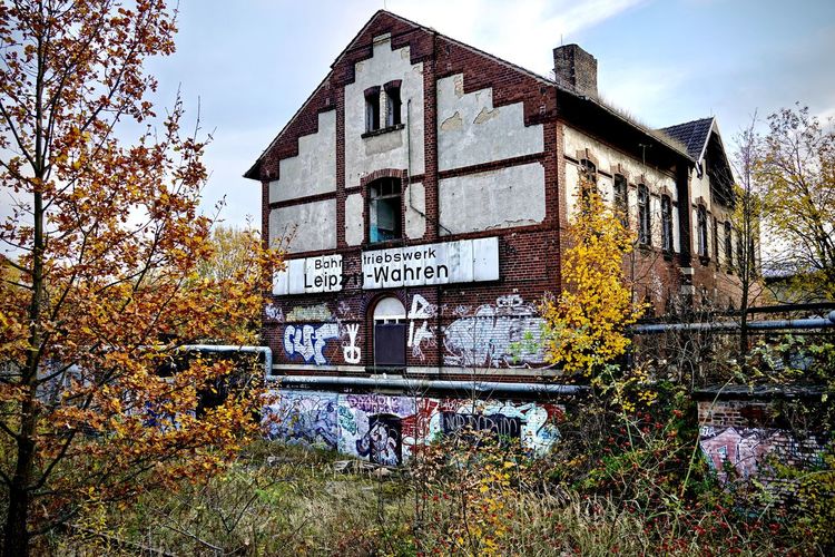 Information sign on abandoned house against sky during autumn