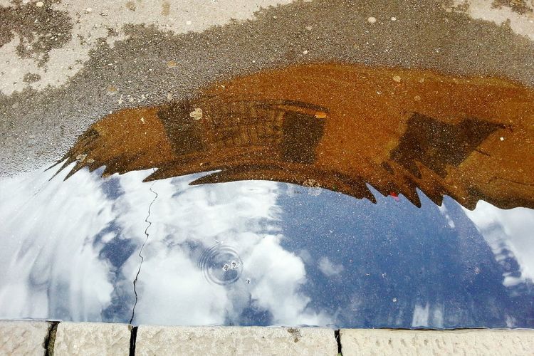 Reflection of sky in puddle on street