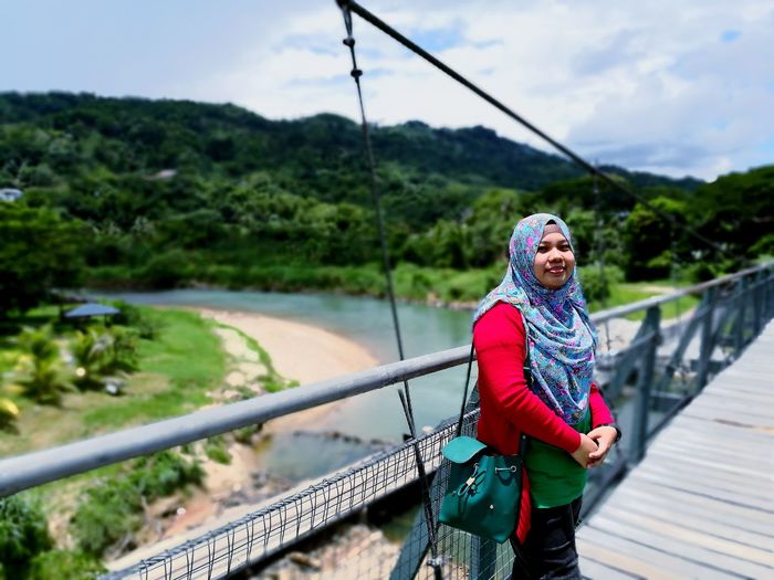 Portrait of young woman wearing hijab on bridge against mountains