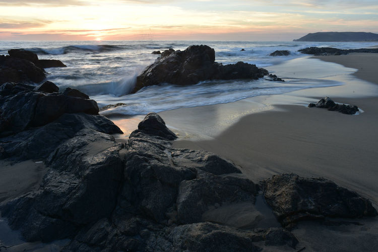 Setting sun on horizon rocky pacific coast beach in baja california sur, mexico