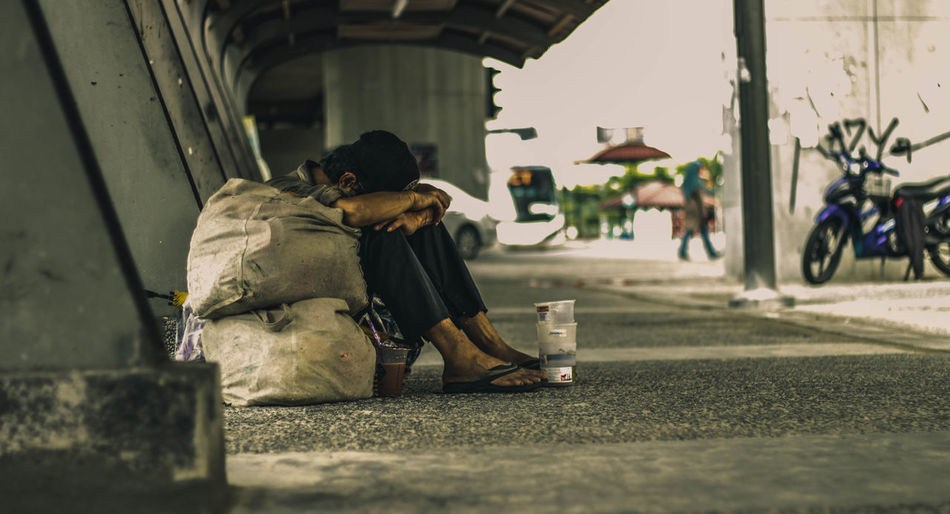 Beggar sitting under bridge