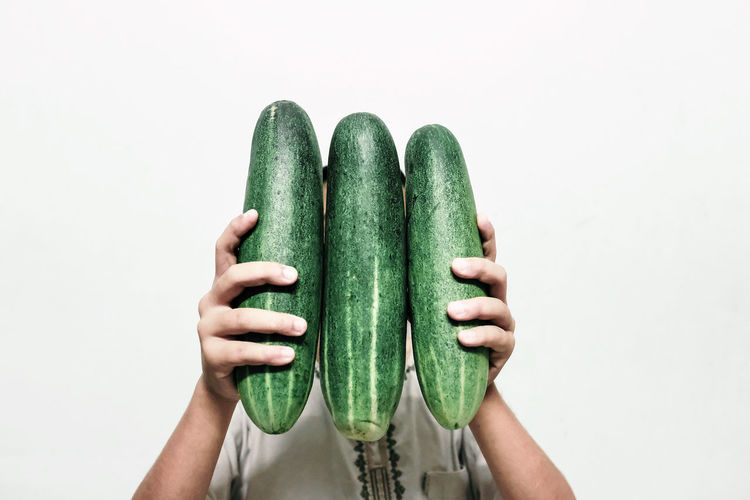 Woman holding cucumber against white background