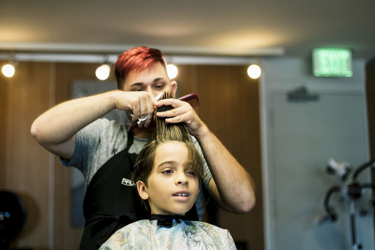 Front view of male cutting boy hair at salon