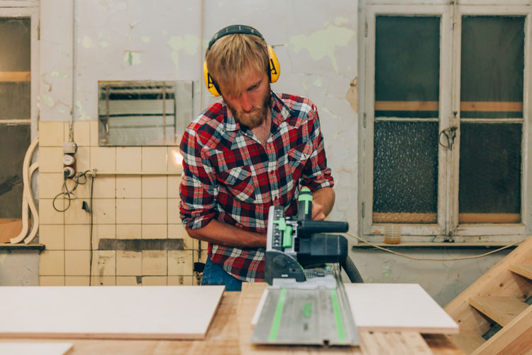 Designer artisan man working with wood while using mowing saw