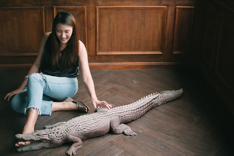 Young woman sitting by crocodile statue on floor