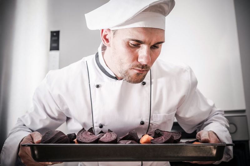 Close up of chef holding beetroot slices in tray at restaurant