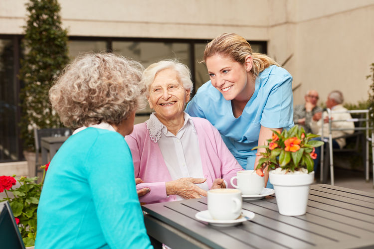 Smiling nurse consoling senior women at nursing home