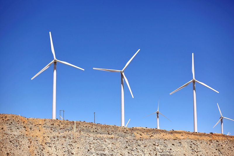 Low angle view of wind turbines on land