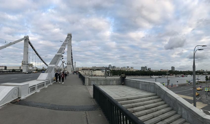 People on bridge in city against sky