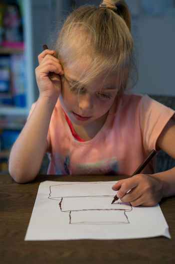 Cute girl drawing on paper at home