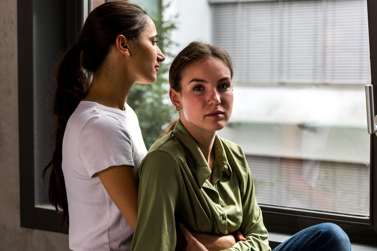 Portrait of woman with lesbian girlfriend against window at home