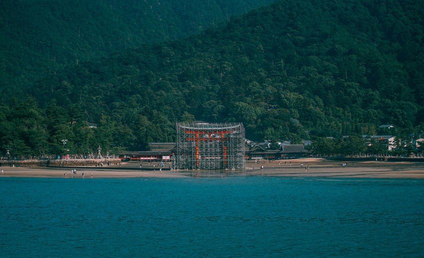 Scenic view of sea against trees and building