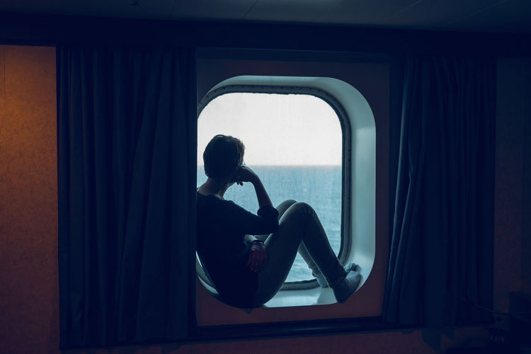 Woman looking at view while sitting at ship window