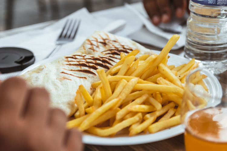 Close-up of french tacos and fries fast food served on table