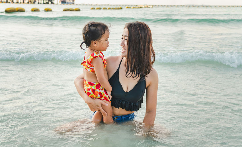 Smiling woman holding daughter at beach