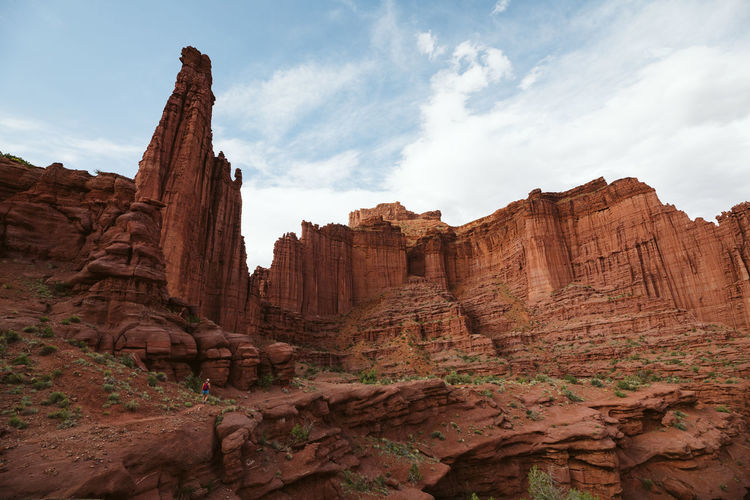 Lone hiker under the red rock formation of fisher tower near moab