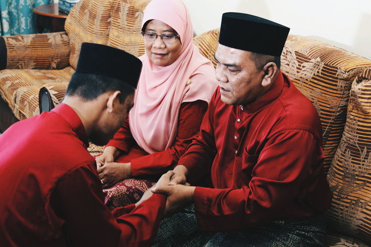 High angle view of siblings wearing traditional clothing while shaking hands at home