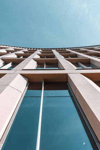 View looking up at building with tap windows against blue sky