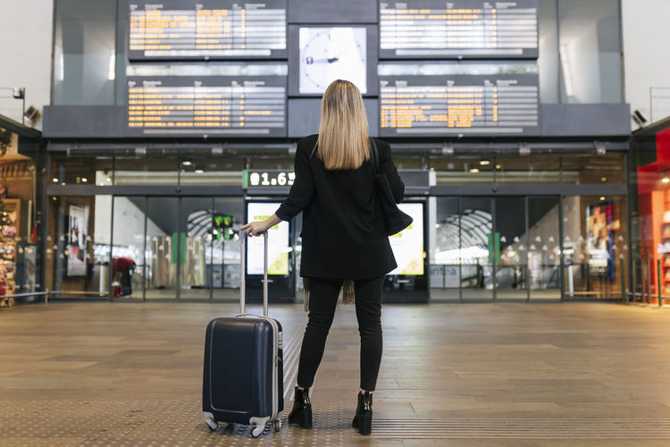 Woman looking at arrival departure board at railroad station
