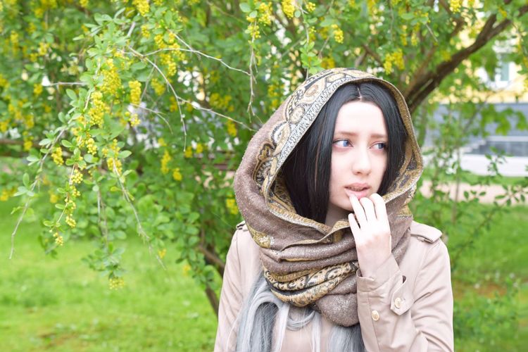Thoughtful young woman in scarf looking away on field