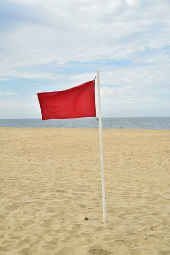 Red flag blowing in wind of seashore