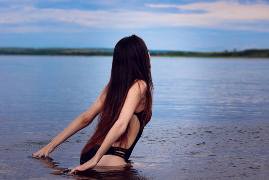 Sensuous young woman standing in sea against sky