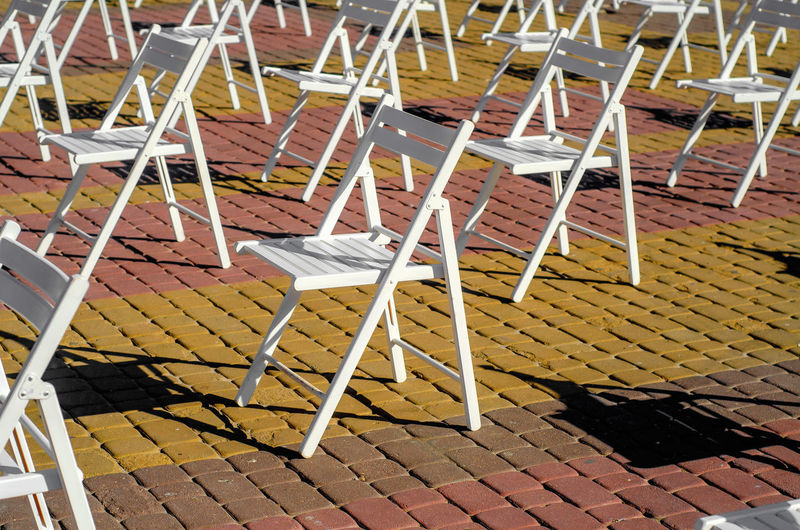 Folding chairs are arranged on recreation area. empty folding wooden chairs in a public square