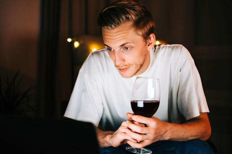 Side view of a young man drinking glass
