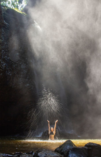 High angle view of woman standing in waterfall