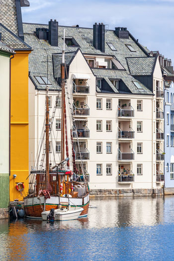 Houses by river against buildings in city