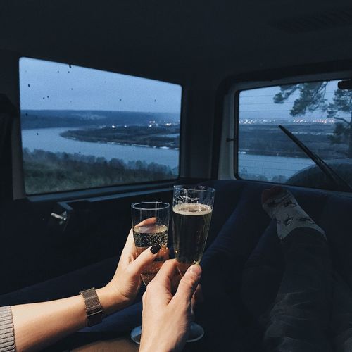 Cropped hands of couple toasting champagne flutes in vehicle