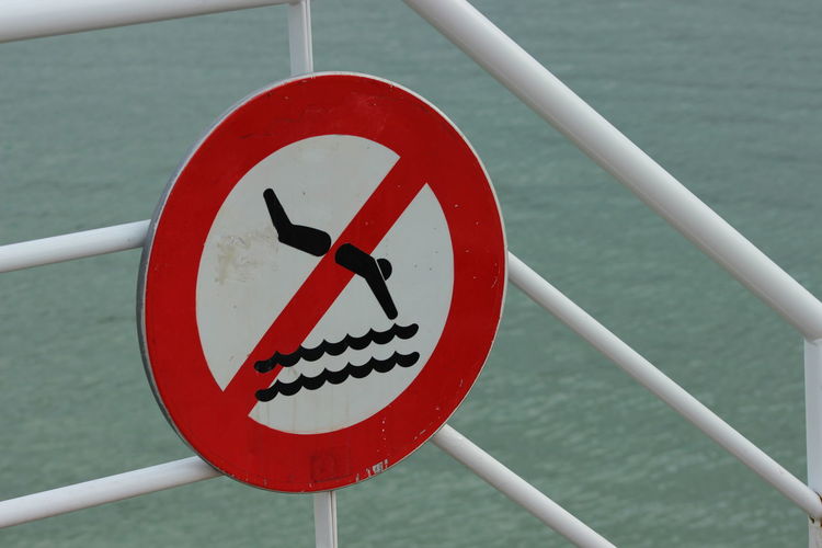 No diving sign on railing against sea