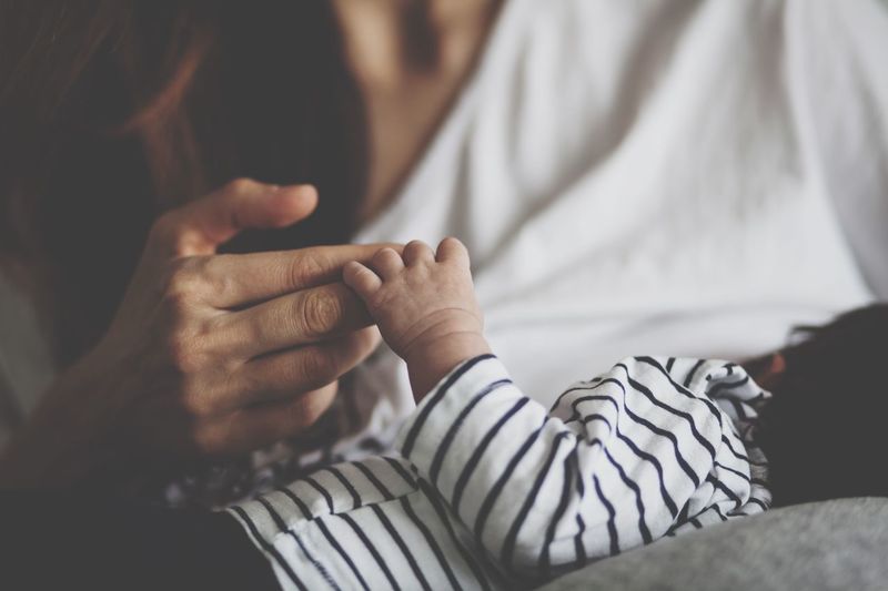Close-up of woman and baby holding hands
