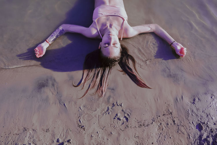 High angle view of woman lying down on sand at beach