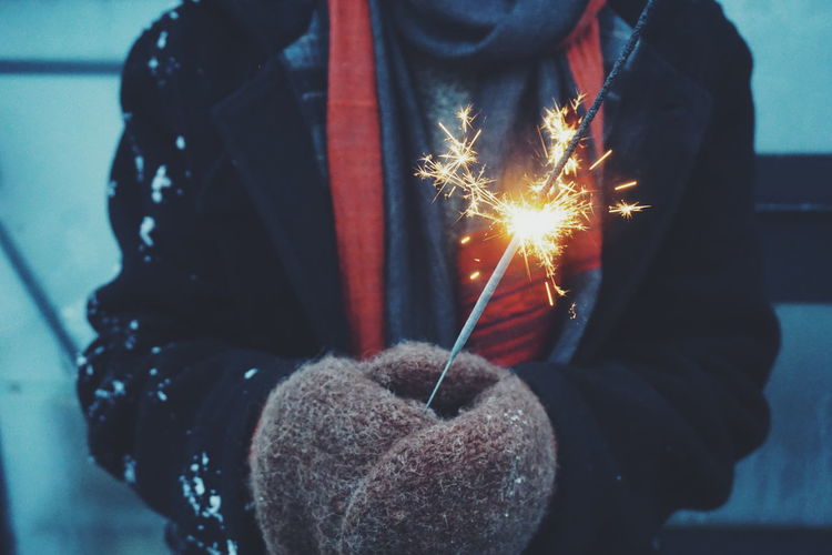 Midsection of woman holding lit sparkler