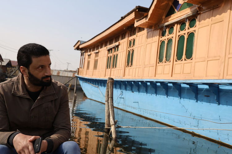 Young man looking away while sitting on boat, houseboat srinagar 