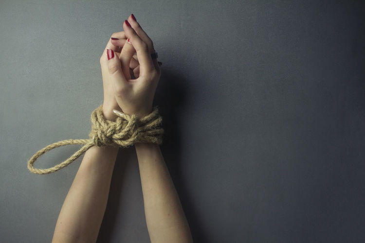 Close-up of hands tied with rope on black background