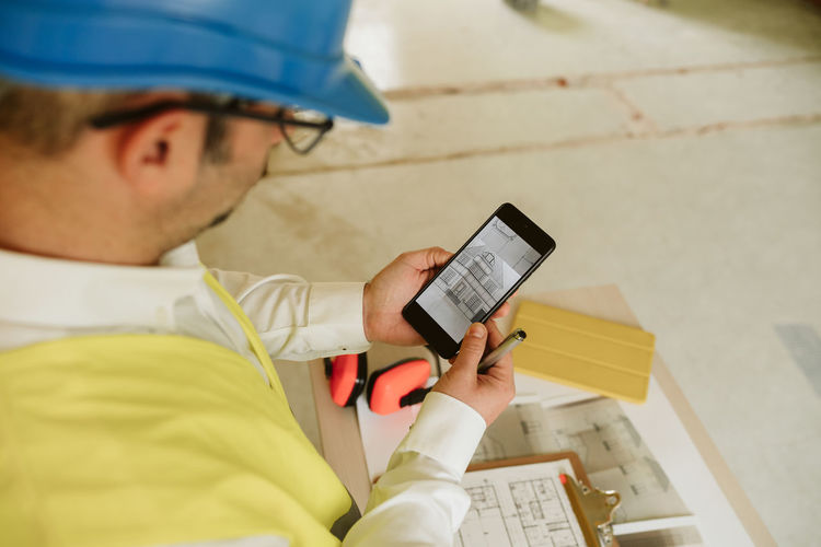 Foreman or architect working on mobile phone blueprints .construction site. home improvement