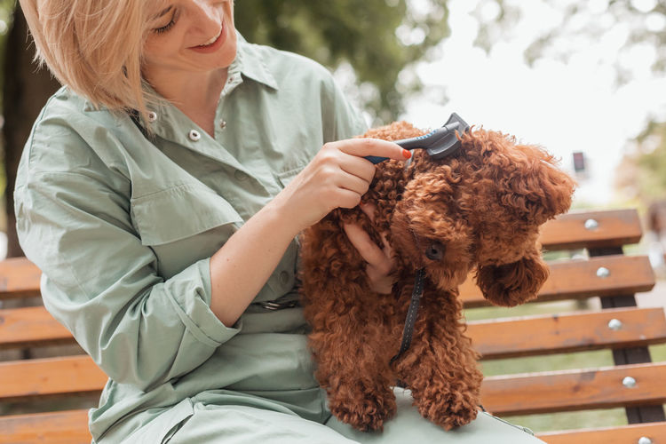 Midsection of woman with dog sitting outdoors