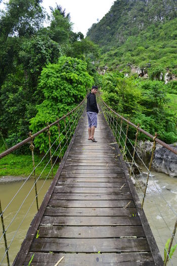 Portrait of man standing on footbridge over river