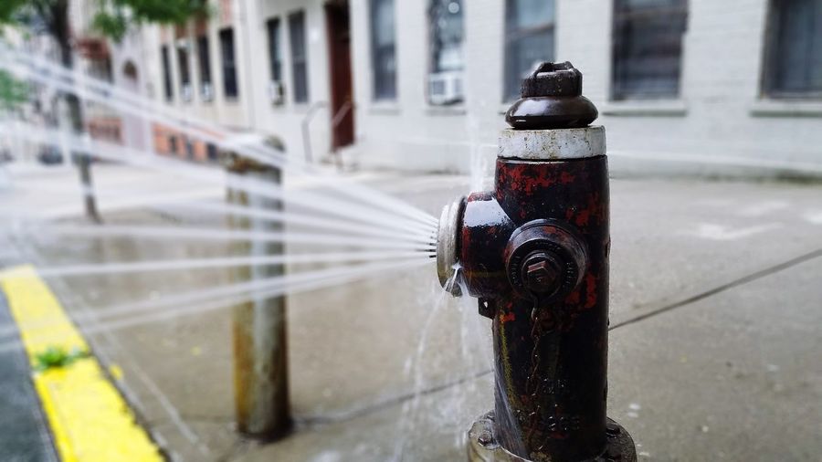 Close-up of water spraying from fire hydrant on sidewalk
