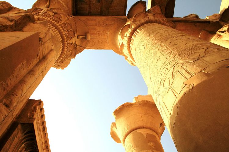 Hieroglyphics on columns against clear sky