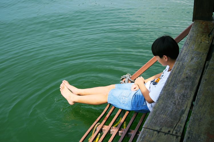 High angle view of boy sitting by lake