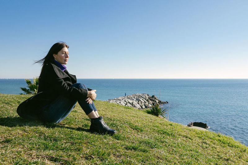 Middle-aged woman meditating in front of the sea on a winter day