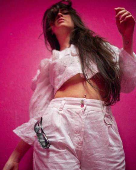 Midsection of woman standing against pink wall